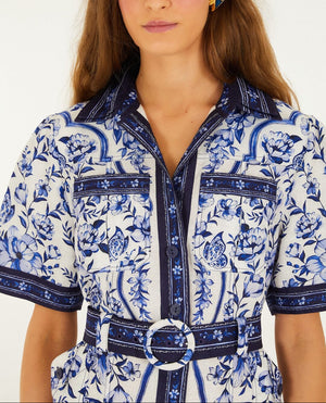 Woman wearing the Porcelain Garden Off White Mini Dress by Farm Rio, featuring blue and white florals, short sleeves, front buttons, chest pockets, and a belted waist.