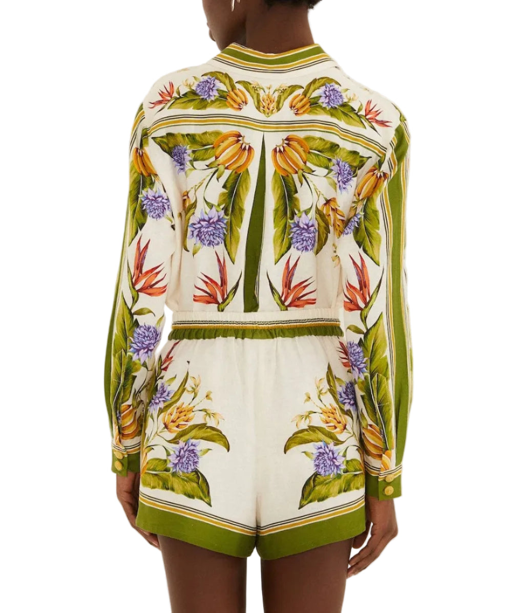 A person wearing Farm Rio's Sand Tropical Scarf Shorts, featuring green stripes and a vibrant tropical floral print, captures effortless summer style, shown from the back.