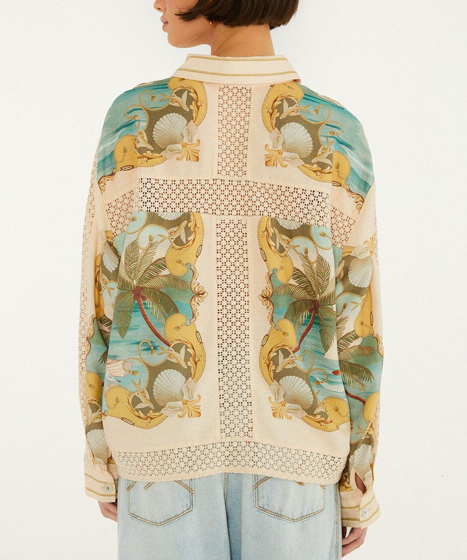 A person with short brown hair is seen from the back, wearing the Farm Rio Royal Sea Crochet Detail Shirt with tropical patterns and light blue jeans, styled with lightweight layering.