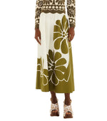 Someone wearing the Farm Rio Palermo Green Midi Skirt, featuring a bold floral print, paired with a matching floral sweater and platform sandals.