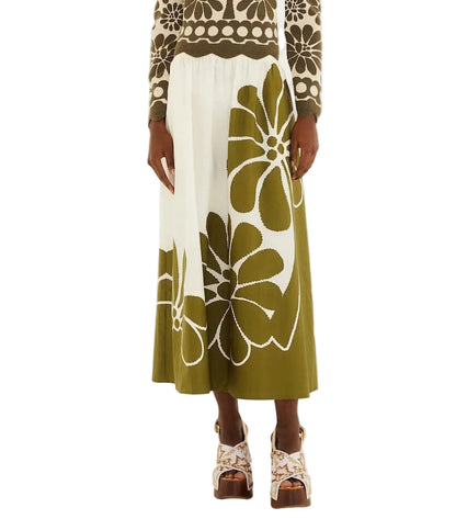 Someone wearing the Farm Rio Palermo Green Midi Skirt, featuring a bold floral print, paired with a matching floral sweater and platform sandals.