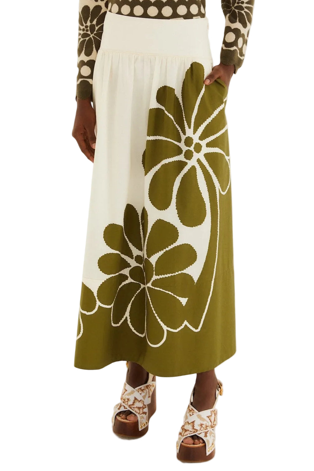 A person wearing the Farm Rio Palermo Green Midi Skirt with bold floral patterns, a patterned long-sleeve top, and platform sandals.