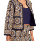 A person wearing a patterned Cara Cara Marissa Jacket and matching skirt set with a navy blue top. The outfit features intricate, circular designs in shades of yellow and white, accented with quilted cotton details.