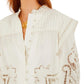 Woman wearing a Farm Rio Richilieu Blouse made from organic cotton, featuring puff sleeves, embroidered and cut-out floral details, a ruffled collar, and a gold necklace.