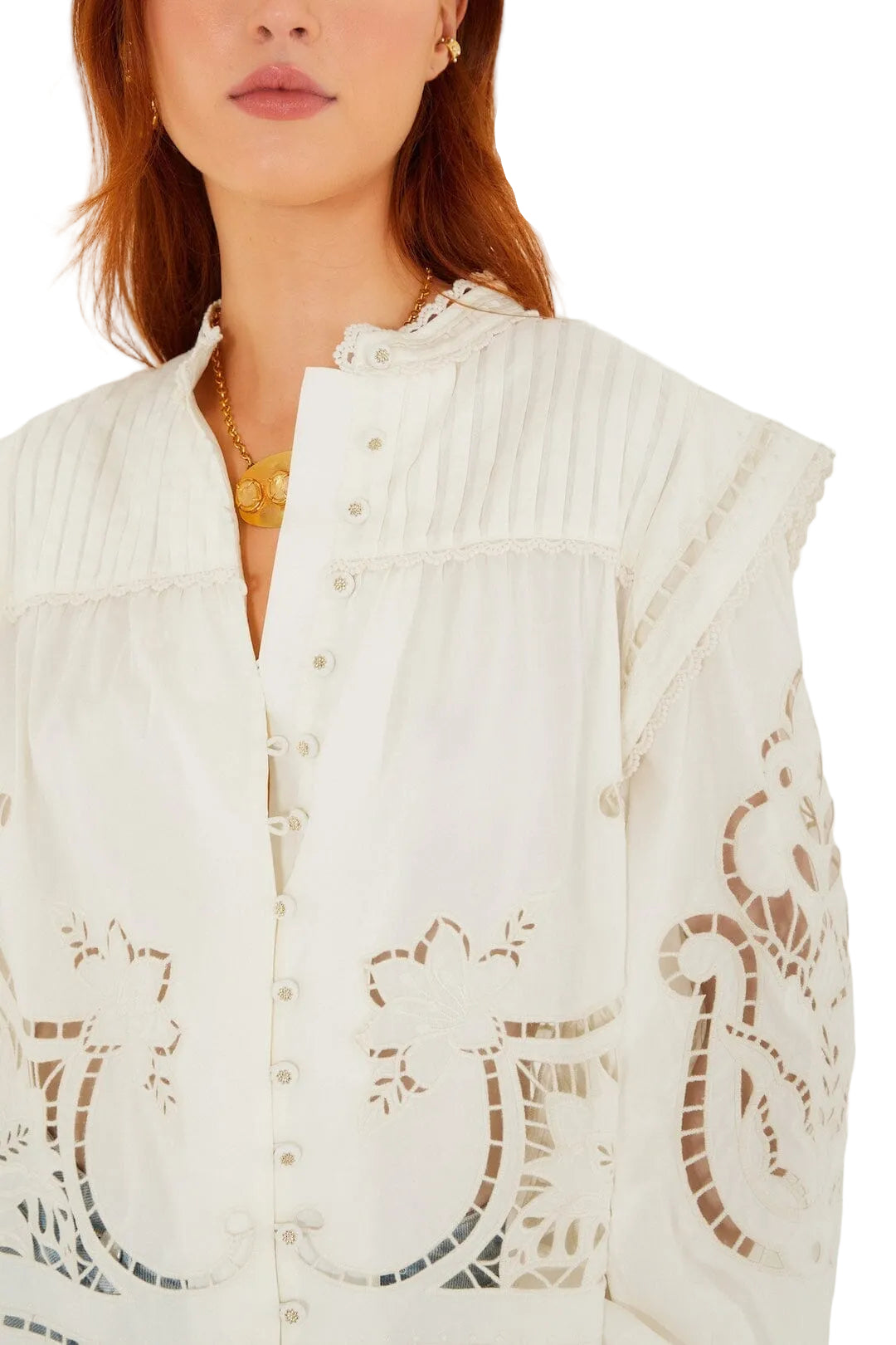 Woman wearing a Farm Rio Richilieu Blouse made from organic cotton, featuring puff sleeves, embroidered and cut-out floral details, a ruffled collar, and a gold necklace.