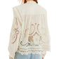 A person wearing a Farm Rio Richilieu Blouse made from organic cotton with detailed cut-out embroidery, paired with light blue jeans, is shown from the back.