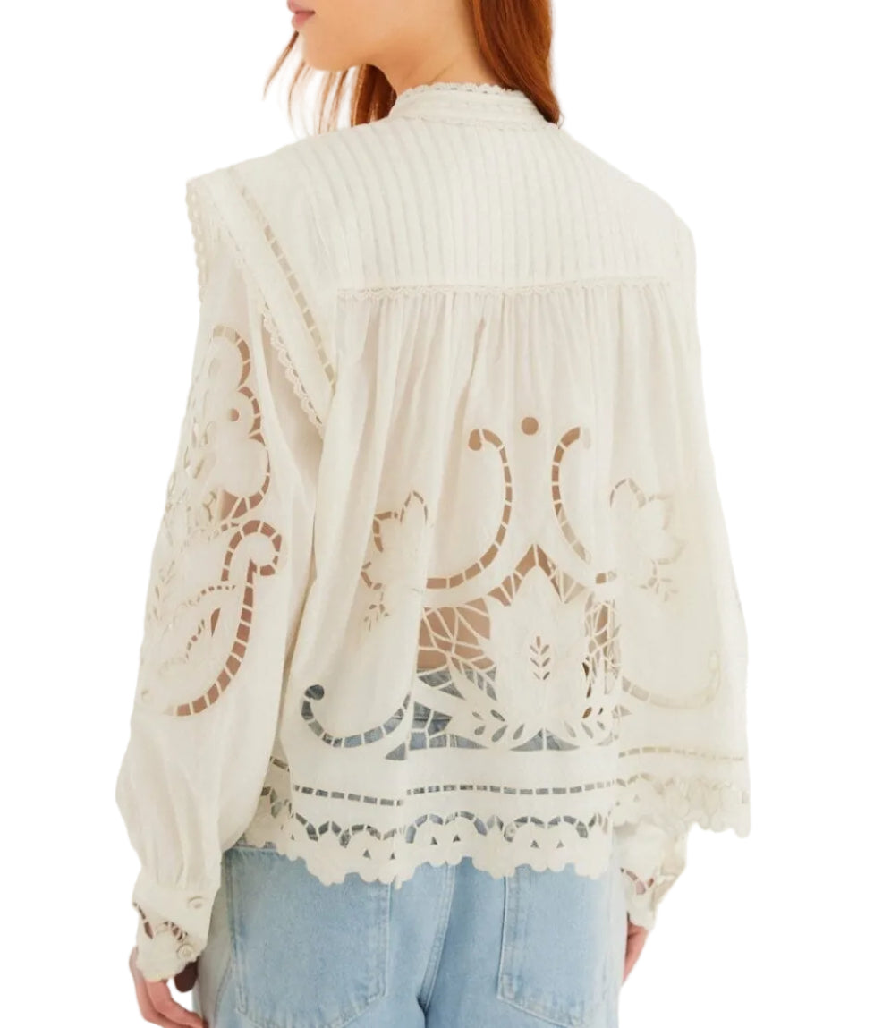 A person wearing a Farm Rio Richilieu Blouse made from organic cotton with detailed cut-out embroidery, paired with light blue jeans, is shown from the back.