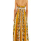A woman is seen from the back wearing the Farm Rio Sand Hilo Stripes Dress, a long, sleeveless yellow and white striped dress with thin straps.