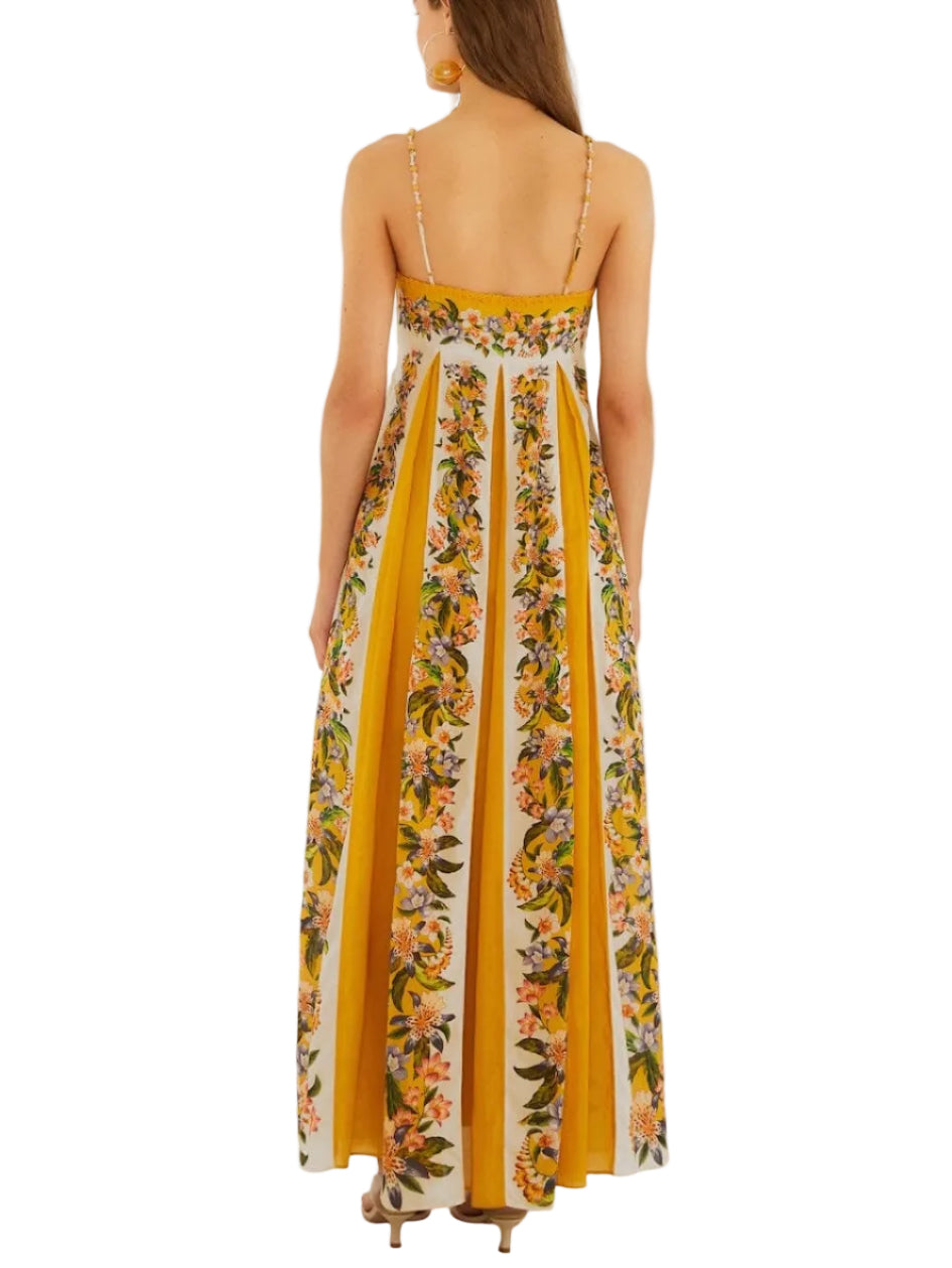 A woman is seen from the back wearing the Farm Rio Sand Hilo Stripes Dress, a long, sleeveless yellow and white striped dress with thin straps.