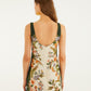 A woman with long brown hair wears the Farm Rio Nature Sand Mini Dress, a sleeveless floral mini with a square neck and scoop back, as she stands against a plain white background.
