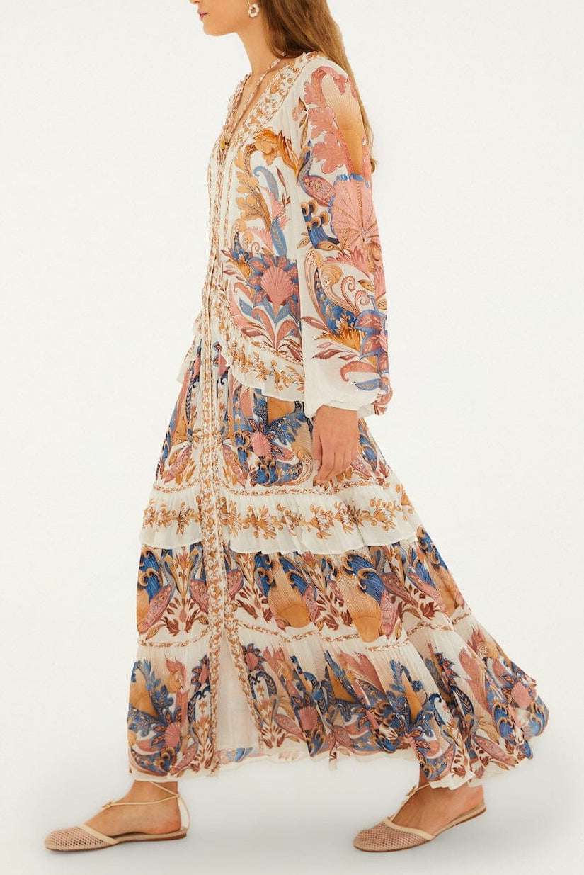 A woman wearing the Farm Rio Sea Garden Off White Braid Details Long Dress walks to the left, paired with flat woven shoes.