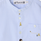 The Baby Boys’ and Boys’ Matis Shirt by Bonpoint is a light blue shirt for babies, detailed with white buttons, a small hand-embroidered hedgehog and fir trees, and “Bonpoint” text above the pocket.