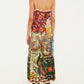 A person wearing a Farm Rio Lunar Boho Maxi Dress, a sleeveless, ankle-length style with colorful botanical patterns, paired with black heeled boots.