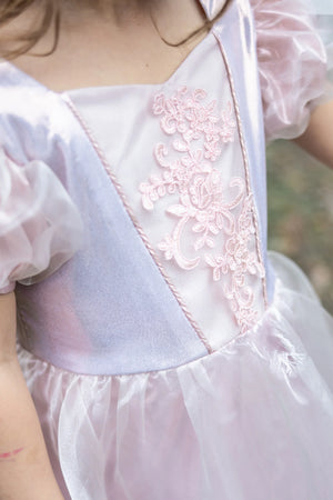 A child wearing the Great Pretenders Platinum Princess Gown, a light pink kids’ dress featuring floral embroidery and sheer puff sleeves, shown from the shoulders to the waist.