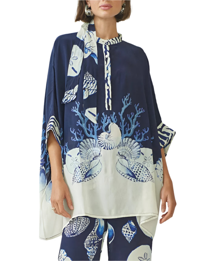 A woman wears the Ayya Mini Dress by Carolina K, a loose-fitting navy and white dress featuring a sea life print with seashell and coral patterns, created in collaboration with a South African artist.