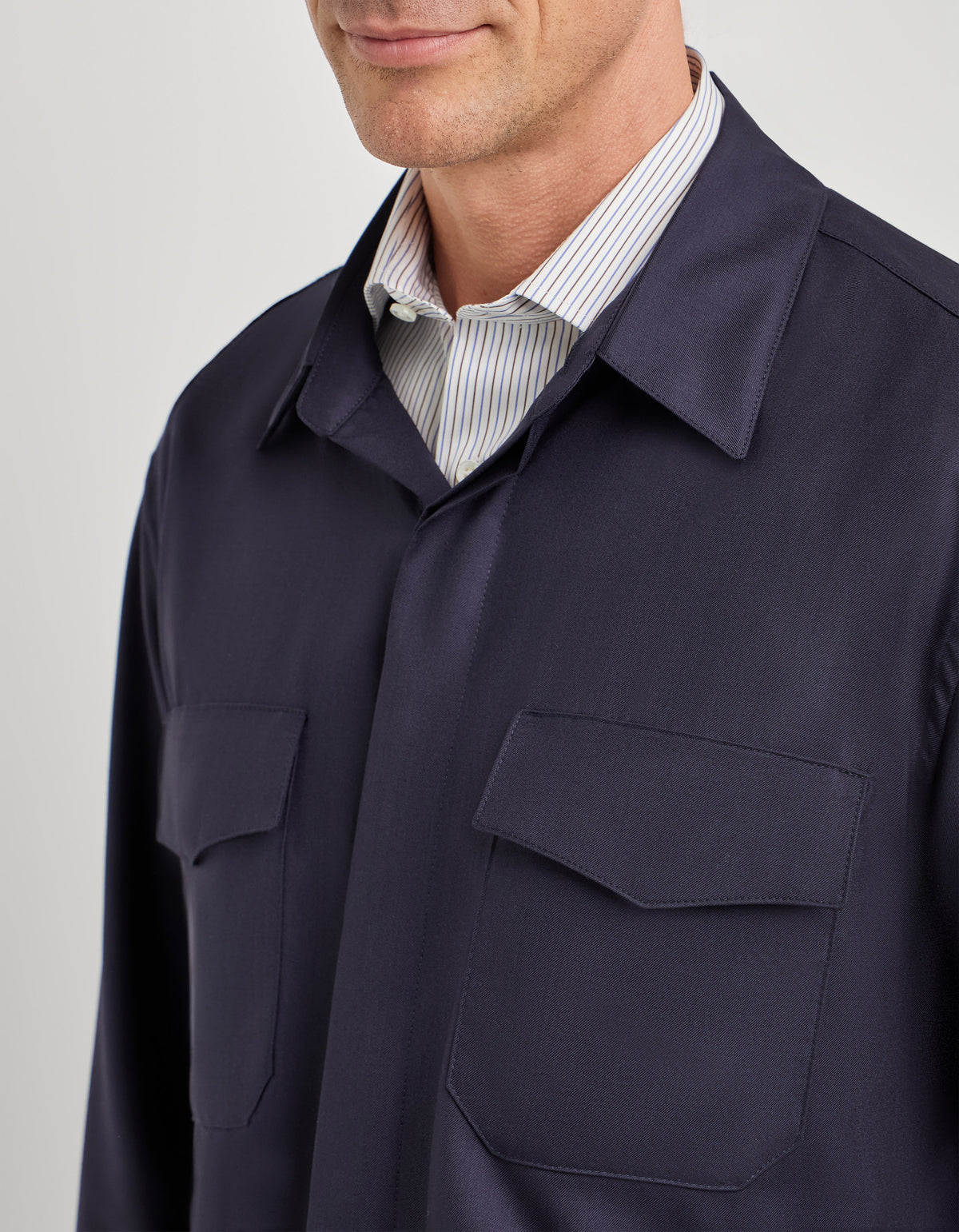 Canali Relaxed Fit Overshirt in dark navy, featuring a relaxed fit and two chest pockets, worn over a striped dress shirt.