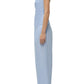 A person stands in profile against a white background, wearing Simkhai’s Arden Pull On Pant—a strapless, light blue pinstriped cotton set with matching wide-leg pants and white sandals.