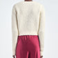 A person is shown from the back wearing the Maria McManus Shrunken V Cardigan in a cream wool-cashmere blend and high-waisted pink pants against a plain background.