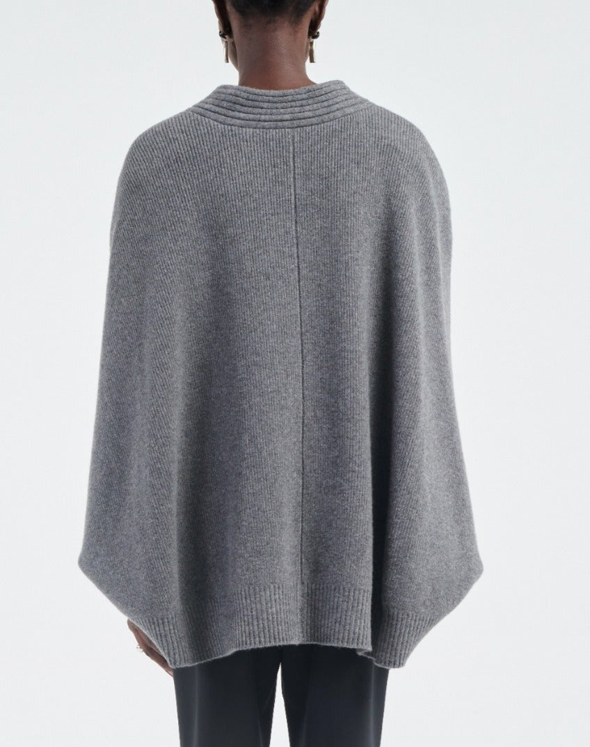 A person is seen from behind wearing the Maria McManus Cocoon Cape, a loose-fitting gray alpaca-wool blend sweater, against a plain light background.