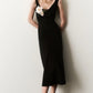 A woman in the Lela Rose 3D Peony Embroidered Fluid Crepe Twisted Detail Dress, featuring a sleeveless black midi design with draped neckline and peony embroidery, pairs it with beige heels against a simple light background.