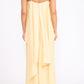 A woman faces away in the Staud Valencia Linen Dress, a light yellow style with adjustable straps and a draped, layered back that enhances its elegant column silhouette.