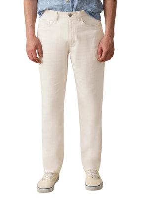 A person wearing Faherty Movement™ Linen 5-Pocket Pant in off-white, paired with a light blue shirt and white sneakers, stands against a plain white background.