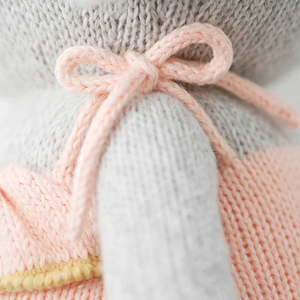 Close-up of Eloise the Elephant - Little 13" by Cuddle + Kind, a savanna stuffed animal in a peach sweater with a pale pink bow—a charming birthday gift to treasure.