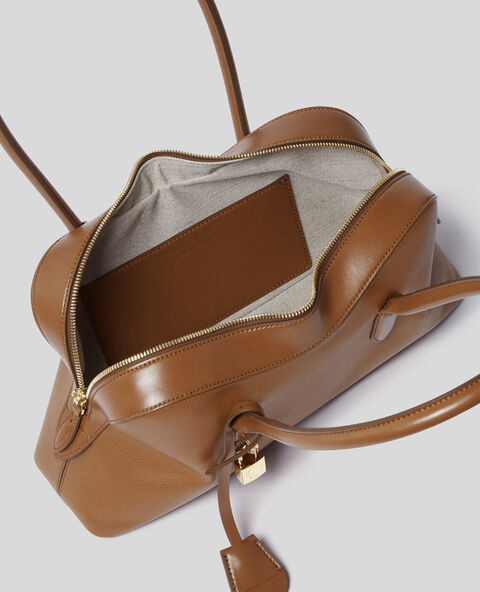 The Stella McCartney Ryder Shoulder Bag is a brown, cruelty-free handbag featuring a gold zipper and padlock on the handle. It opens to reveal a light-lined interior with an inner brown pocket.