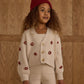 A young child with curly hair wears the Rylee & Cru Baby Girls' and Girls' Boxy Crop Cardigan, standing in front of a wooden wall.