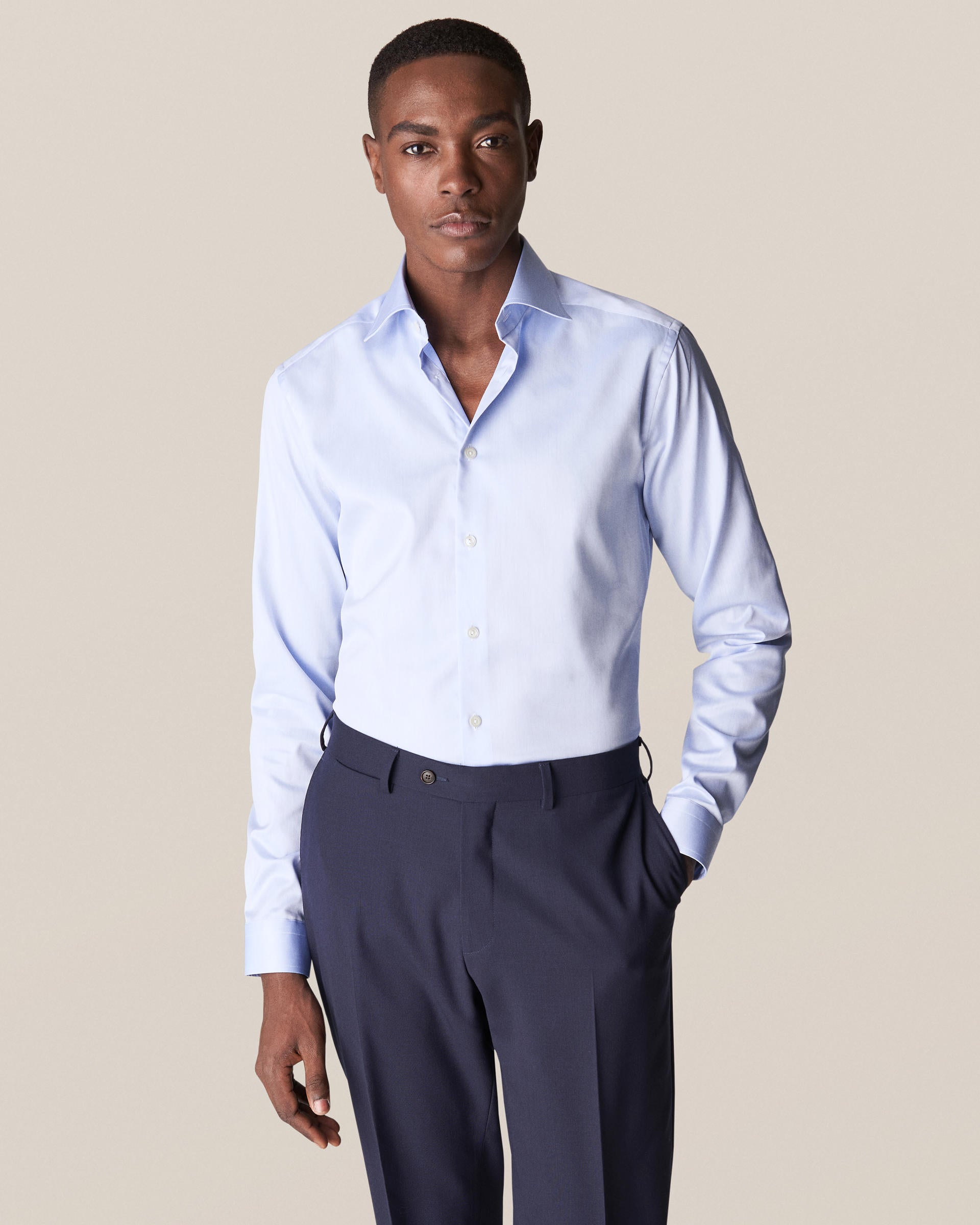 A person wearing the Eton Light Blue Signature Twill Shirt, Slim Fit, paired with dark trousers stands against a plain background, highlighting the shirt's wrinkle-free finish.