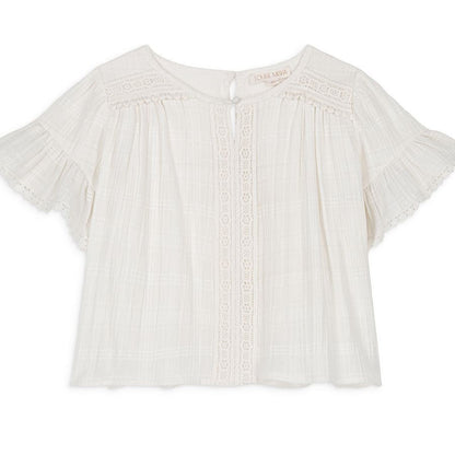 The Girls' Feliza Blouse by Louise Misha is an elegant white summer top with a round neck, delicate lace trim, and pleated detailing. Crafted from lightweight cotton and lace fabric, it features short sleeves and a back button closure for an effortlessly chic look.