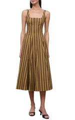 Wearing the Staud Wells Midi Cotton Poplin Dress, a sleeveless olive and brown striped midi dress with a square neckline, paired with block-heeled sandals, a woman stands against a white background, capturing the signature STAUD silhouette.