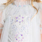 A child wearing the Tutu du Monde Girls’ Snow Queen Tutu Dress, featuring a light blue hue, ruffled collar, iridescent beaded star and flower designs, and sheer tulle skirt details—perfect for an enchanting ice queen costume.