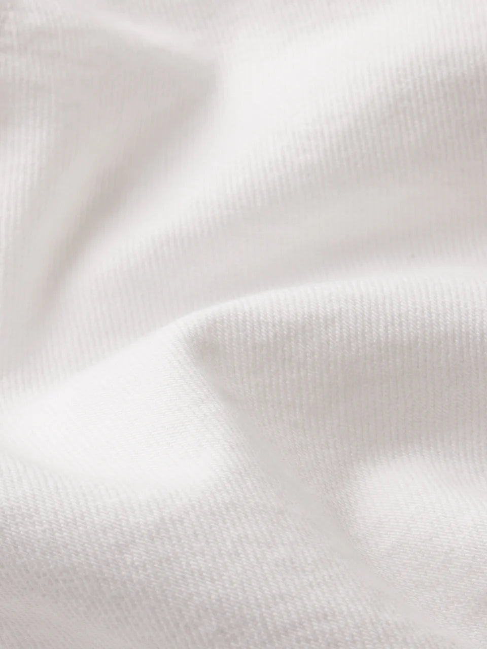 Close-up of a white, textured fabric with visible weave and soft folds, ideal for The Long Hang Short by Frame—offering a relaxed, effortless style.