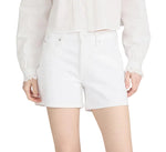 A person wears Frame’s The Long Hang Short, a relaxed-fit white high-waisted short with a 4½” inseam, styled with a white long-sleeve blouse and standing with hands by their sides.