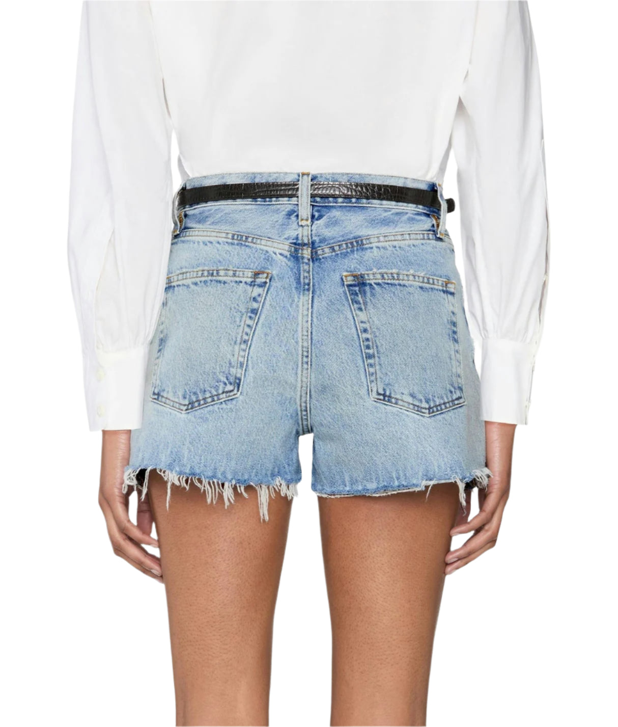 Model wears The Dare Short by Frame—light blue, mid-rise denim cut-offs—paired with a white long-sleeve shirt, seen from the back for a subtle vintage vibe.