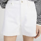 A person wears a black and white striped long-sleeve shirt tucked into Frame’s The Everyday Short—pure cotton, high-rise tailored shorts with a 4" inseam.