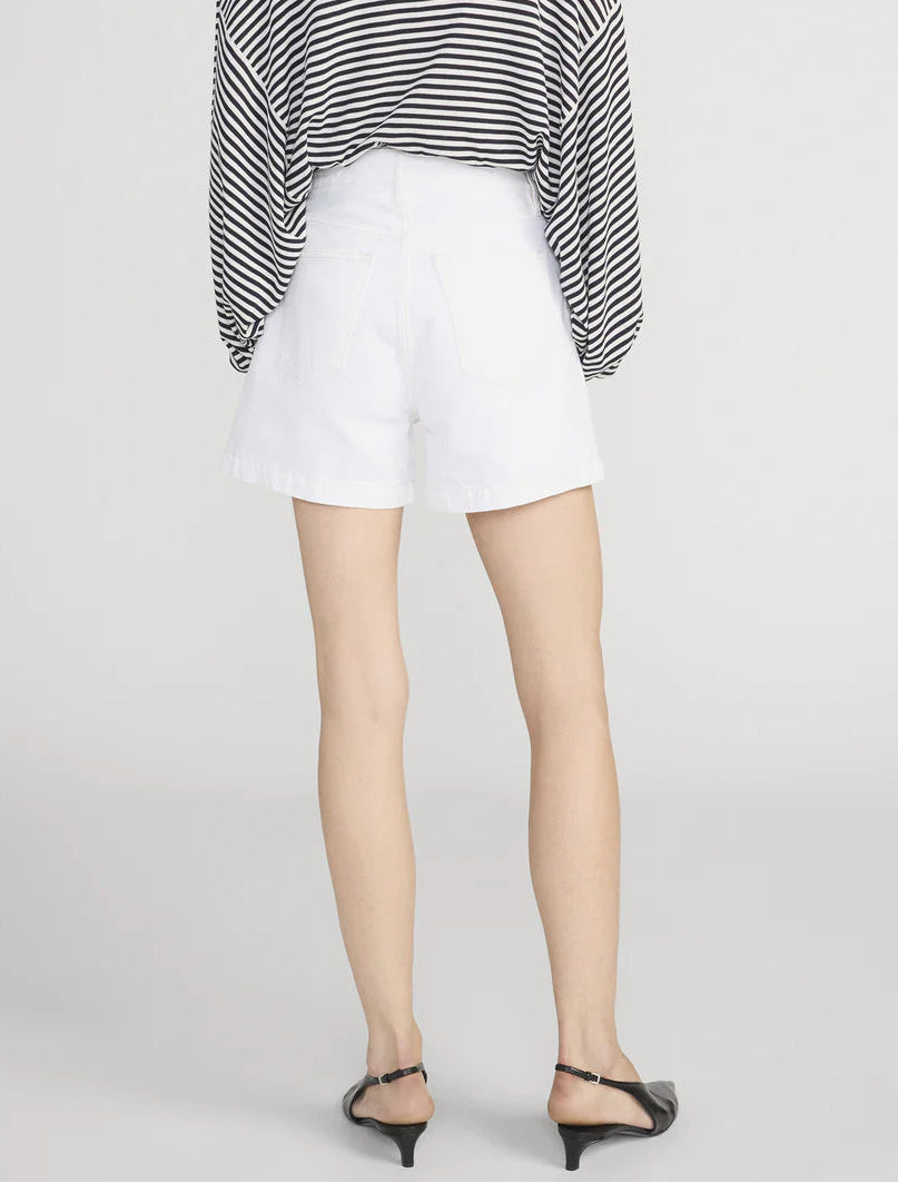 A person stands facing away, wearing a black and white striped top, The Everyday Short by Frame (pure cotton, high-rise, 4" inseam), and black heeled sandals.