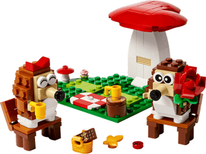 Two hedgehog LEGO figures enjoy a picnic with cups, food, and a large mushroom in the LEGO® Hedgehog Picnic Date set by Legos - Toyhouse—the perfect animal toy build or playful gift for fans of whimsical scenes.