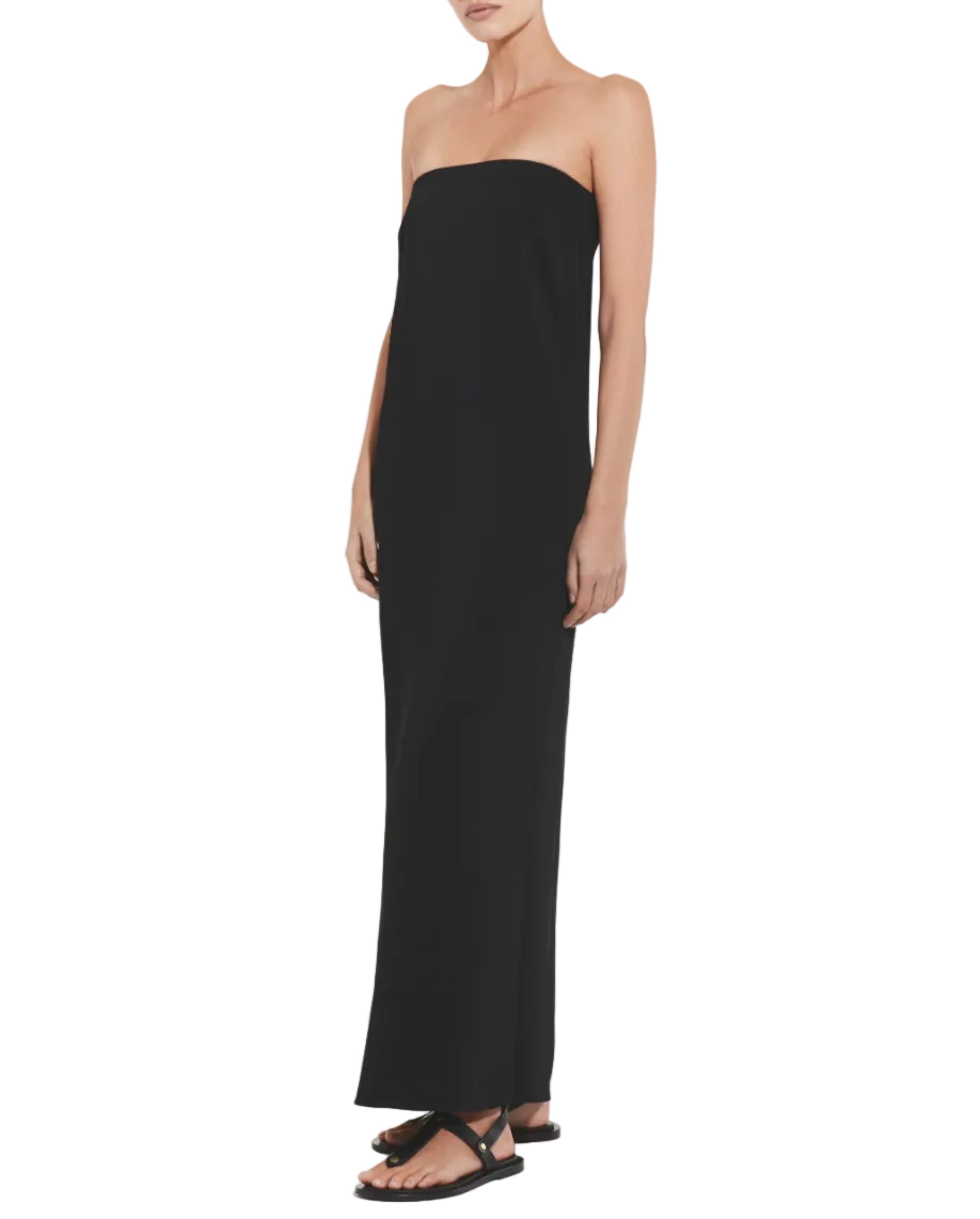 A woman models the CO Strapless Dress in black with matching sandals against a white background—an elegant, formal look.