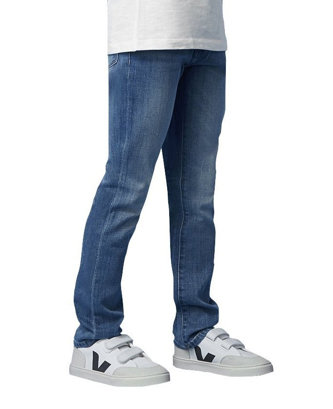 Person standing in DL1961 Brady Slim Jean and white sneakers with a white t-shirt visible at the top.