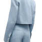 A person is seen from the back wearing TWP's "Drink At Costes" light blue washed hemp denim suit, featuring a cropped blazer with shoulder pads and high-waisted pants.