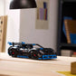 A LEGO® Technic™ Porsche GT4 e-Performance Race Car by Legos - Toyhouse sits on a wooden desk in a modern, well-lit room with books and folders in the background.