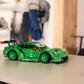 The LEGO® Technic™ Porsche 911 GT3 R REXY AO Racing Car by Legos - Toyhouse, complete with decals, is shown on a light table in a room featuring shelves, coats, and wall decor in the background.