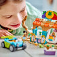 A child joyfully plays on the floor with a vibrant toy set, featuring a small car and market stall embellished with fruit decorations, reminiscent of a LEGO® Friends Beach Smoothie Stand from Legos - Toyhouse.