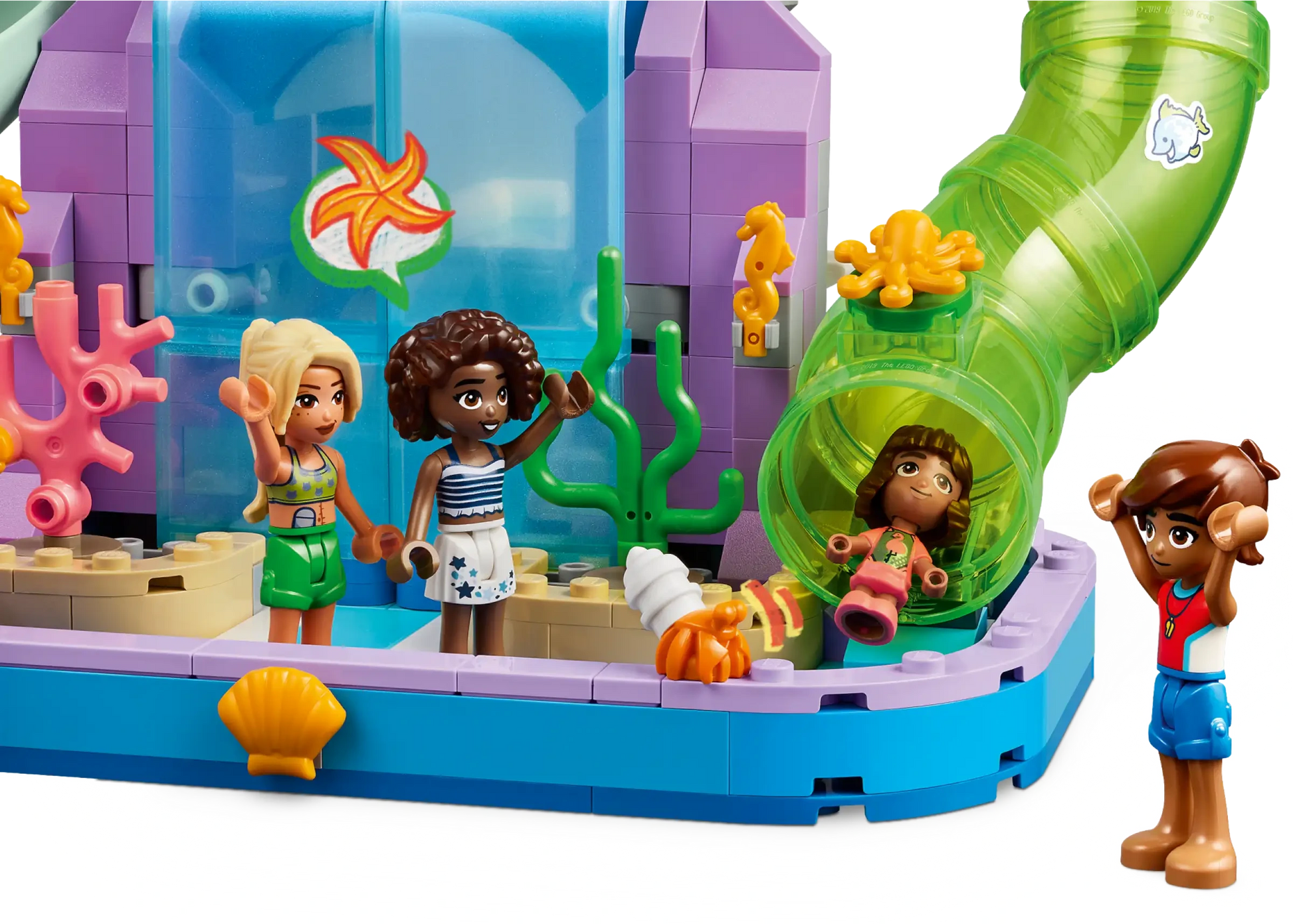 Four mini-doll figures enjoy aquatic fun in the LEGO® Friends Heartlake City Water Park by Legos - Toyhouse, with sea décor, a green tube slide, and a starfish window backdrop—perfect for creative kids’ imaginative play.