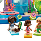 Three toy figures sit on mats with books and speech bubbles in front of the LEGO® Friends Heartlake City Water Park by Legos - Toyhouse, featuring plants and coral—perfect for kids’ imaginative role play.