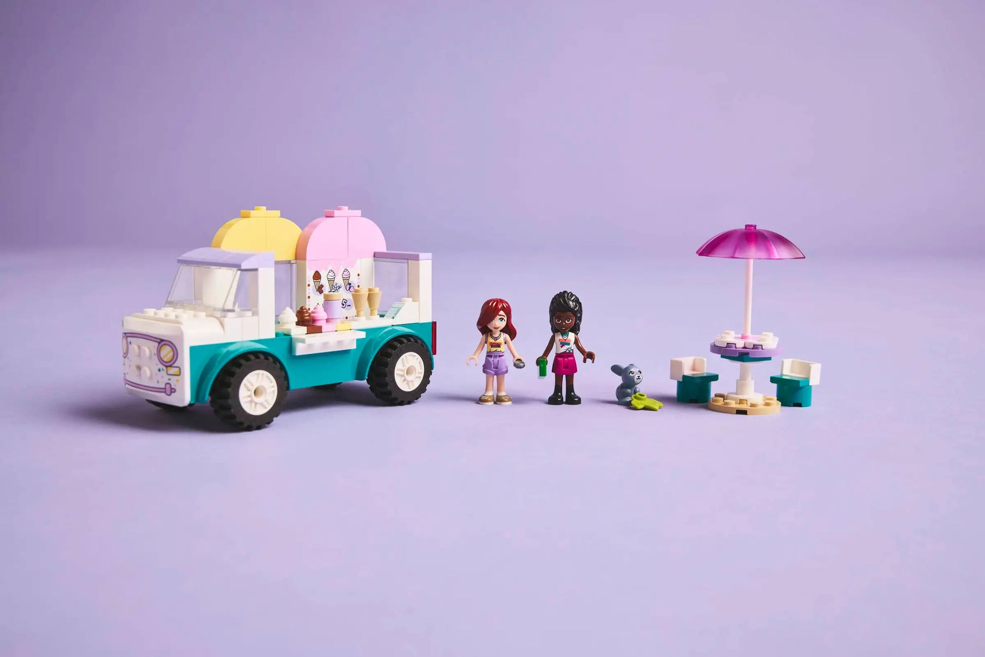 The LEGO® Friends Heartlake City Ice Cream Truck by Legos - Toyhouse includes two mini figures, a small dog, table with umbrella, and ice cream accessories—ideal for pretend play on a vibrant purple background.