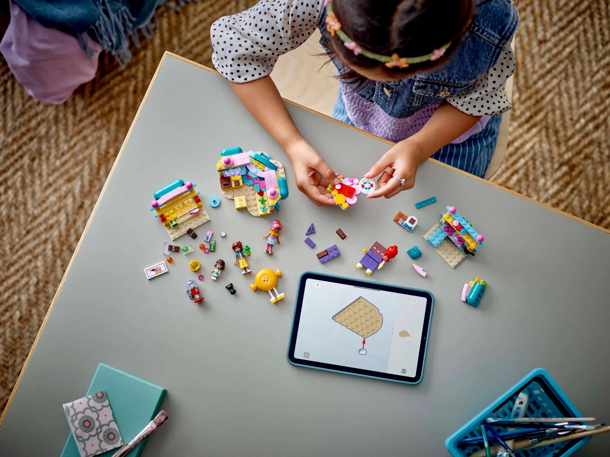 A child builds with colorful pieces from the LEGO® Friends Heartlake City Candy Store by Legos - Toyhouse, following digital instructions on a tablet.