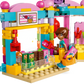 A LEGO figure with a basket stands before the LEGO® Friends Heartlake City Candy Store by Legos - Toyhouse, complete with candy pieces and a checkout counter—ideal for imaginative pretend play.